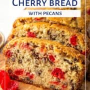 slices of cherry bread with pecans on a wooden board next to a small bowl of maraschino cherries.