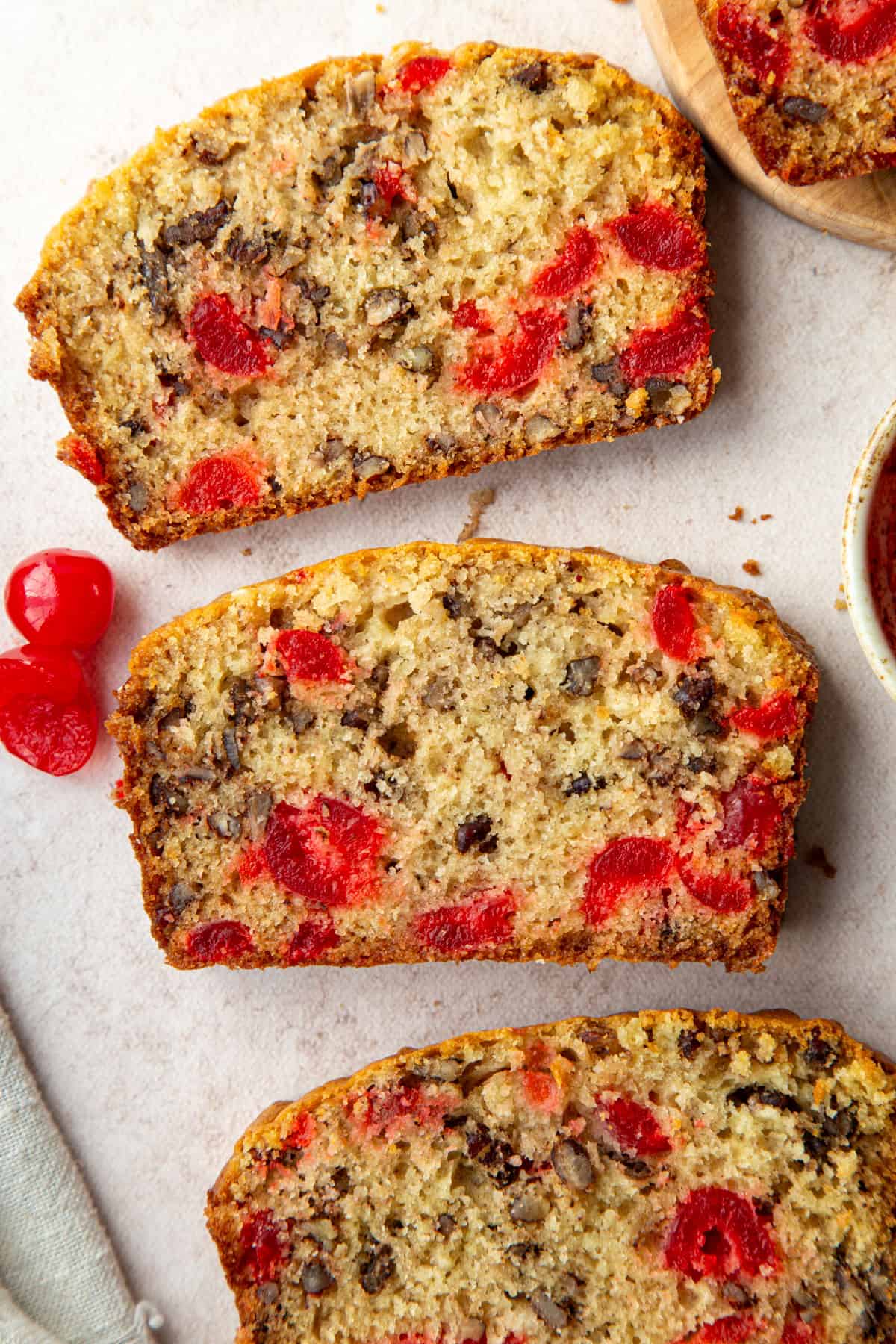 three slices of cherry bread with maraschino cherries and pecans.