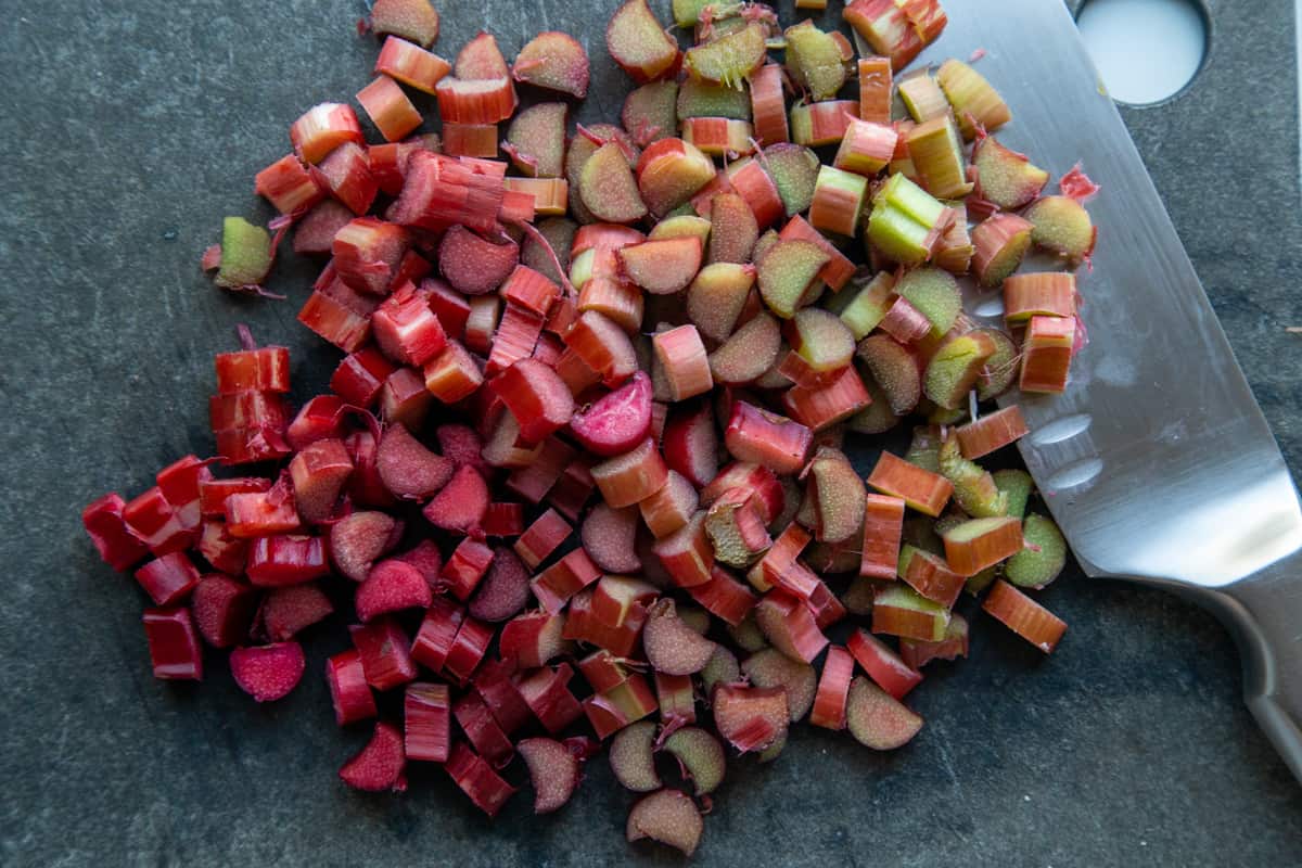 chopped rhubarb and a knife on a black cutting board. 