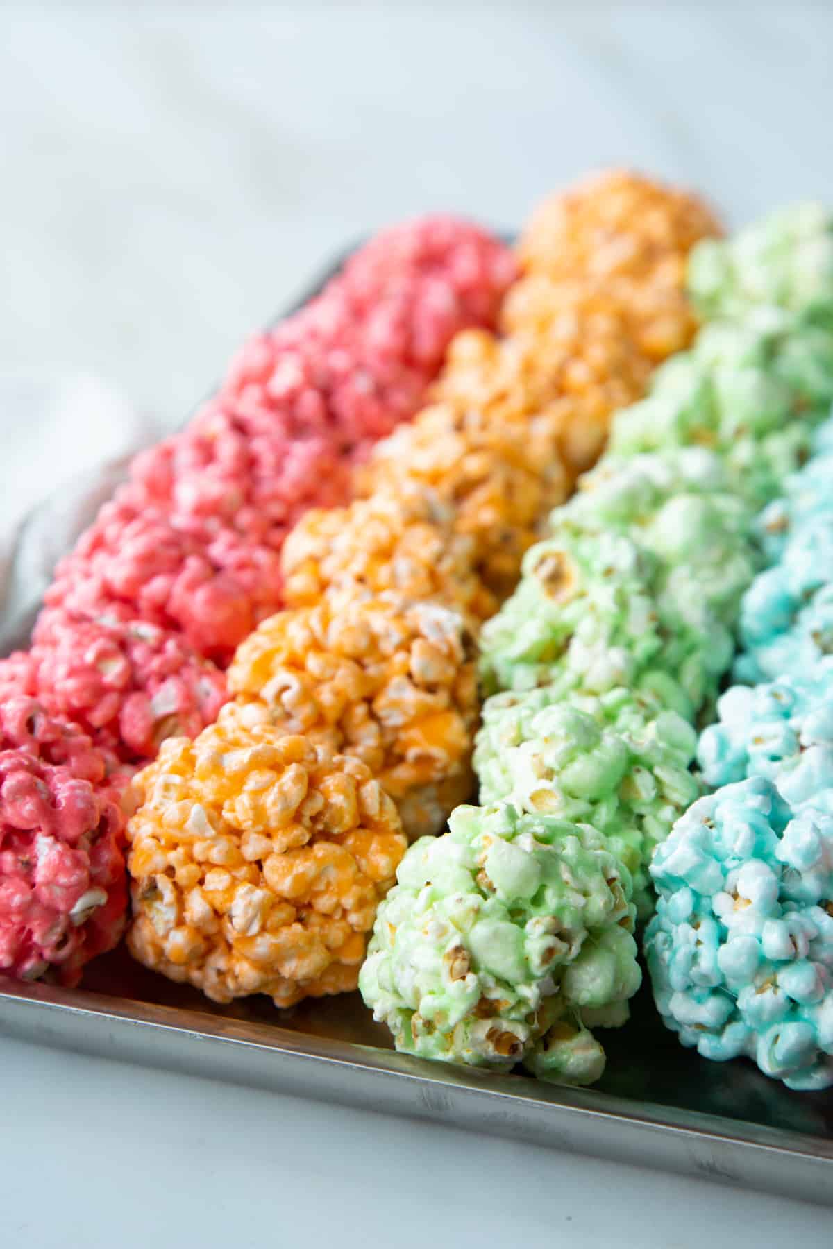 rows of colorful marshmallow popcorn balls on a sheet tray.