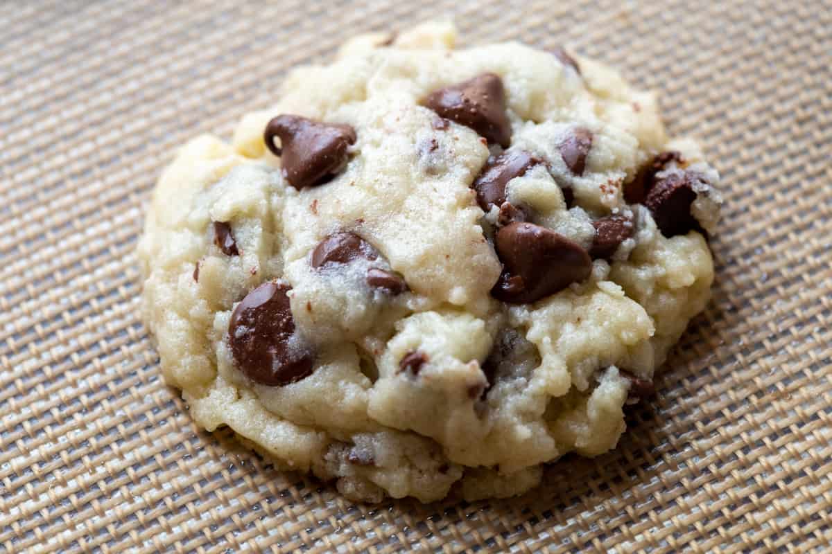 a single cream cheese chocolate chip cookie on a silicone baking mat.