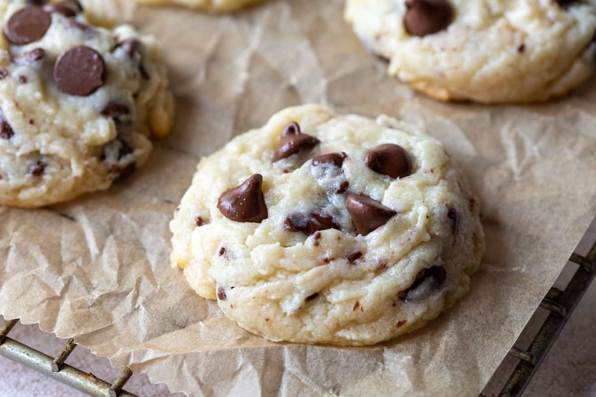 chocolate chip cookies topped with more chocolate chips on a piece of brown parchment.