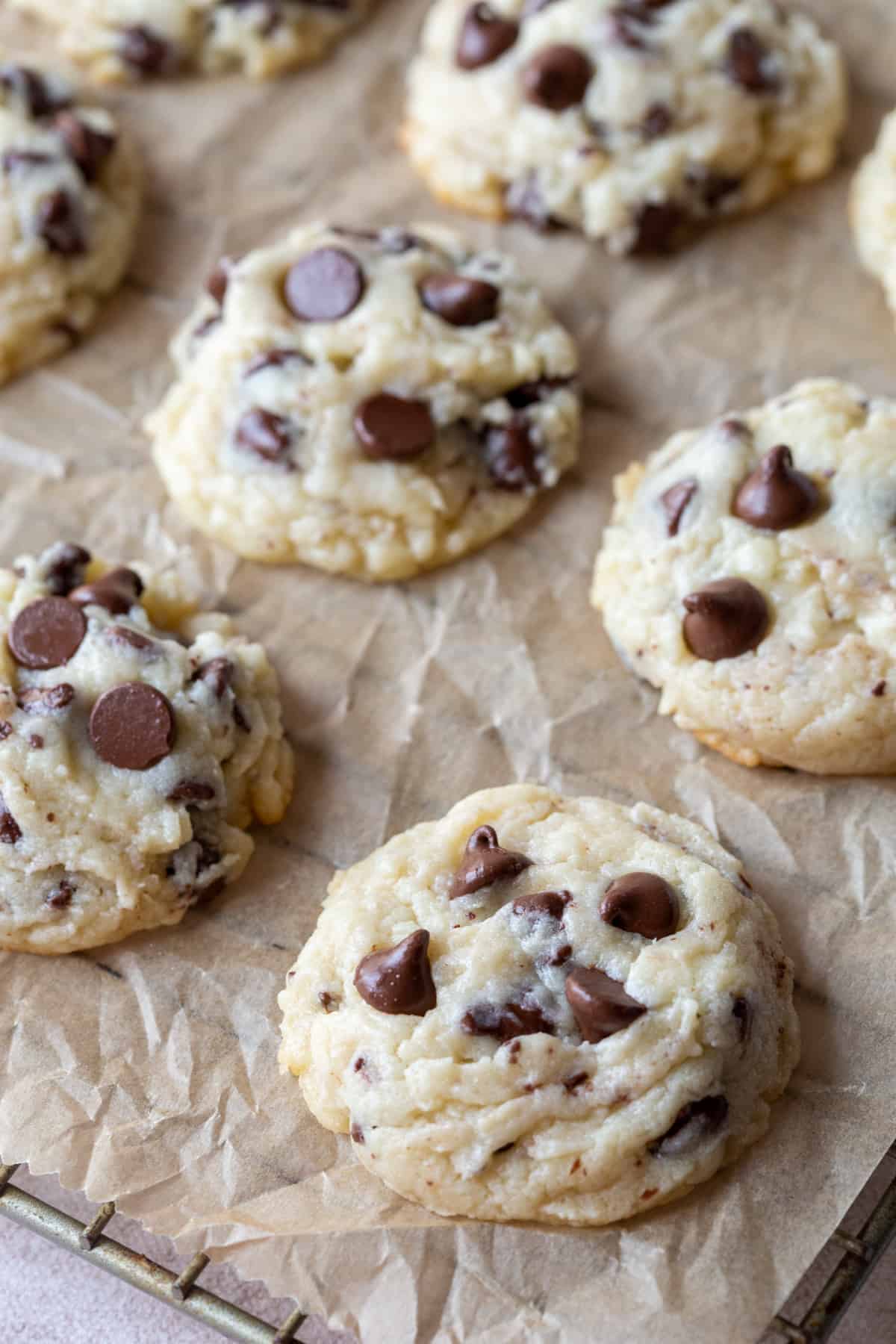 cream cheese chocolate chip cookies on brown parchment on top of a wire rack.