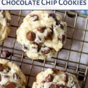 cream cheese chocolate chip cookies on a wire rack next to a few chocolate chips and a blue tea towel.