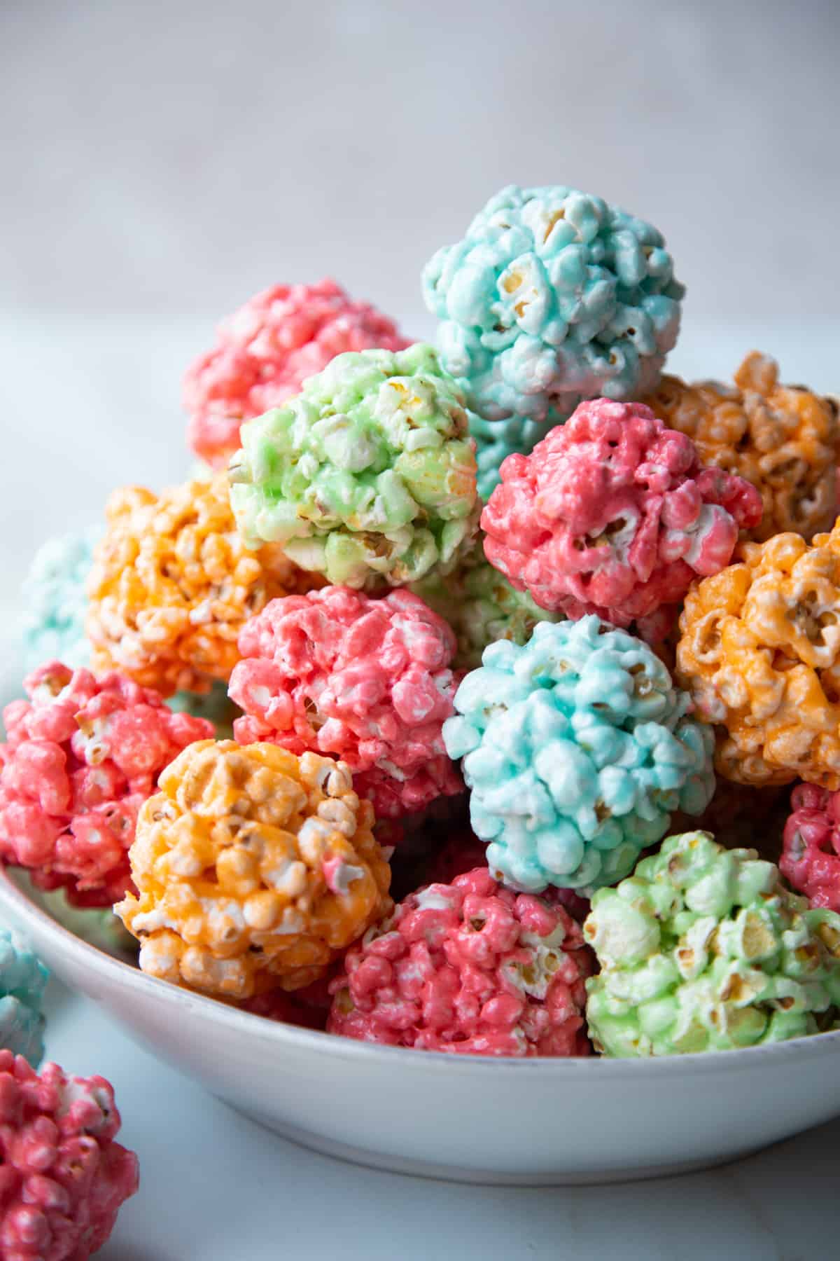 colorful marshmallow popcorn balls stacked in a low white bowl.