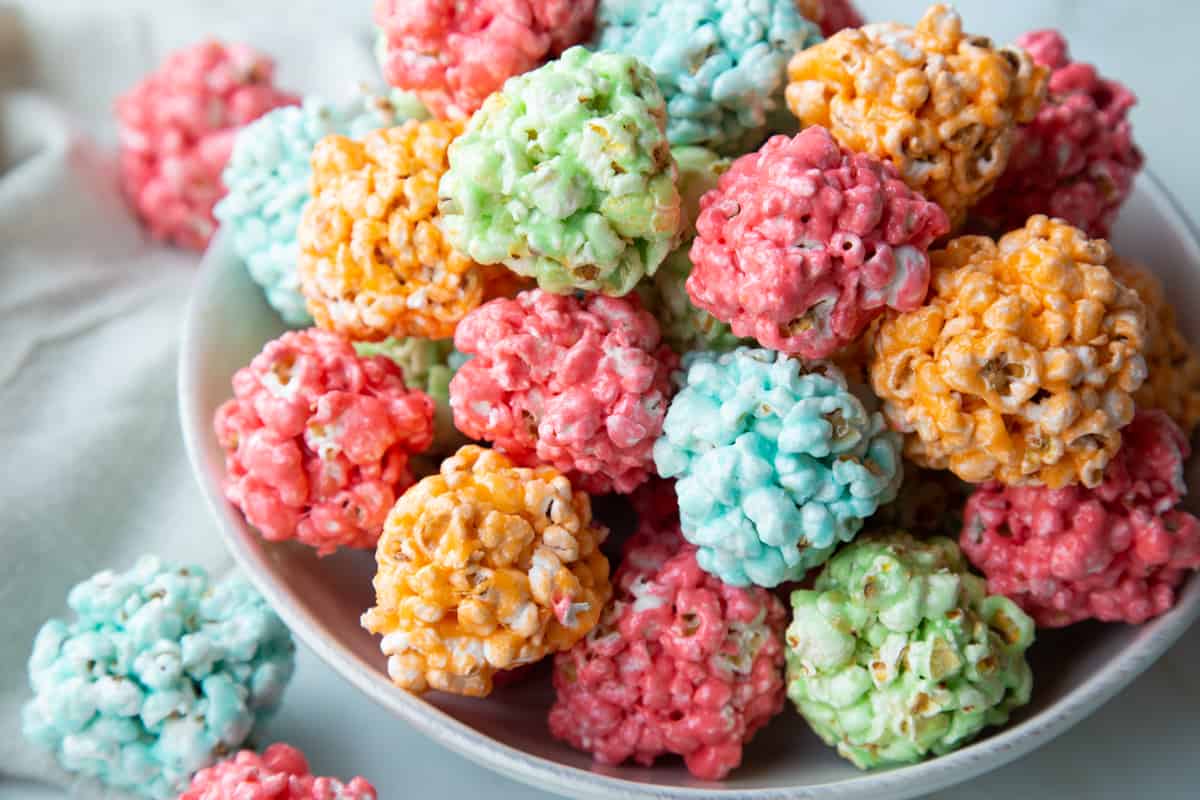 white bowl filled with multi-colored popcorn balls.