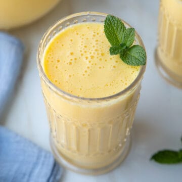 homemade orange julius in a decorative glass, garnished with fresh mint.
