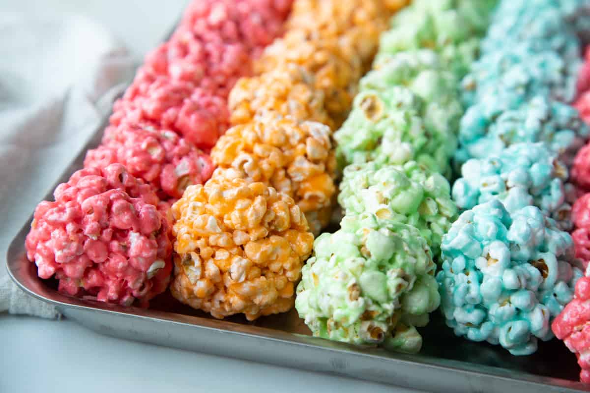 rows of colorful marshmallow popcorn balls on a metal sheet pan.