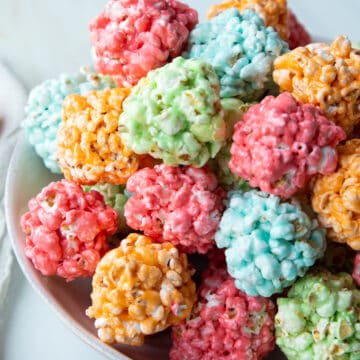 colorful marshmallow popcorn balls stacked into a low white bowl.