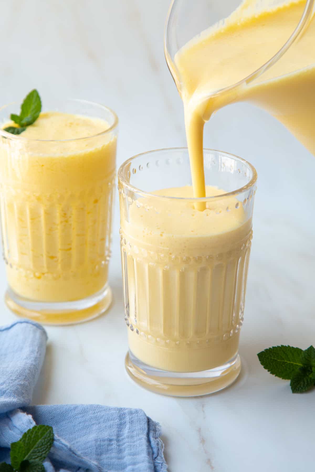 an orange julius being poured from a blender into a decorative glass.