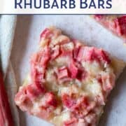 rhubarb bars on a white background, next to a stalk of fresh rhubarb.