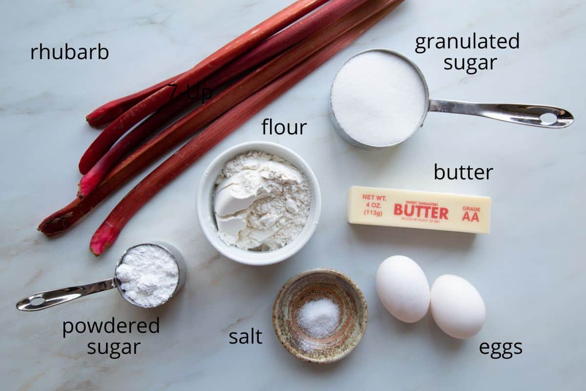 rhubarb, sugar, eggs, and other ingredients on a white table.