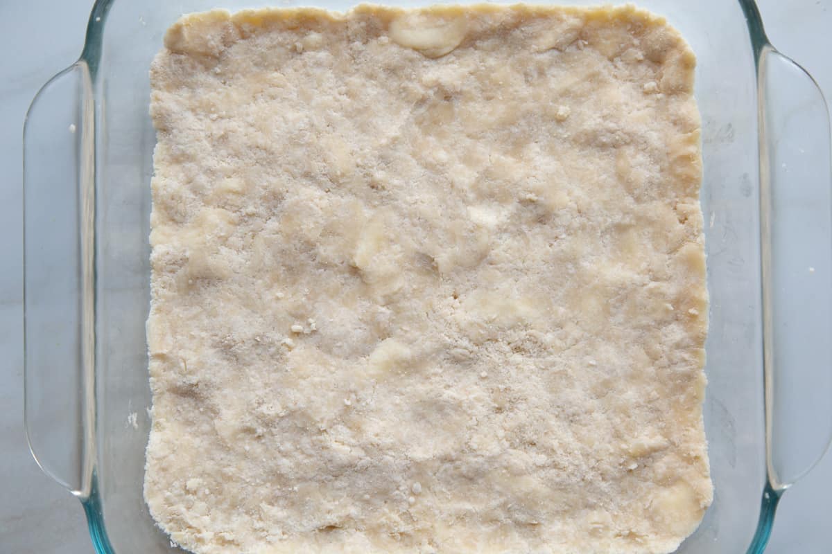 shortbread crust packed into a square glass dish.