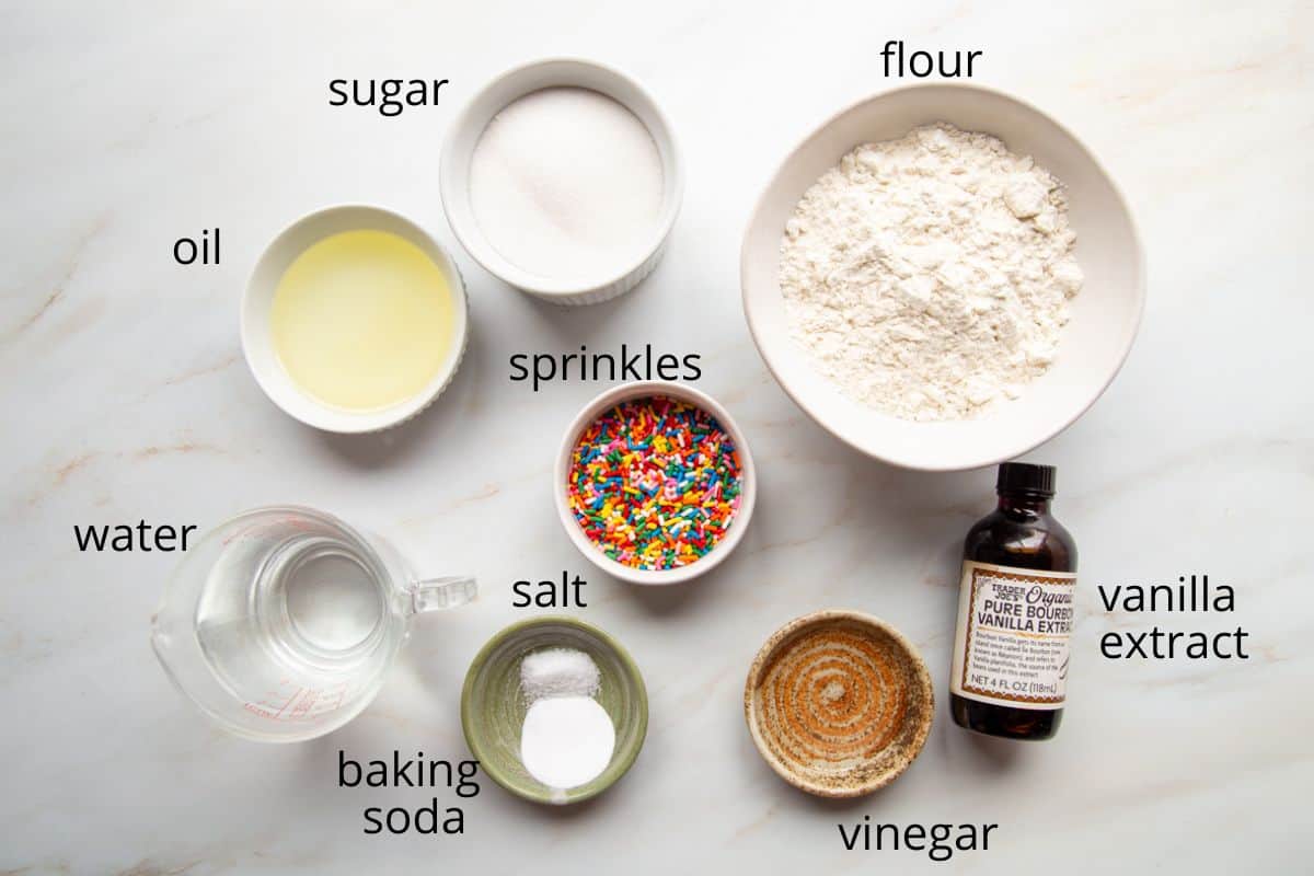 flour, sugar, oil, and other ingredients on a white marble counter.