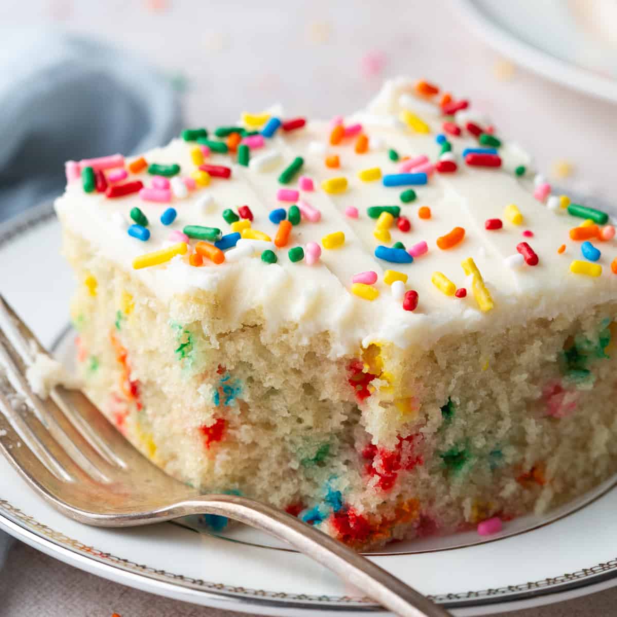 vanilla wacky cake slice on a white plate with a bite taken out and a fork in front.