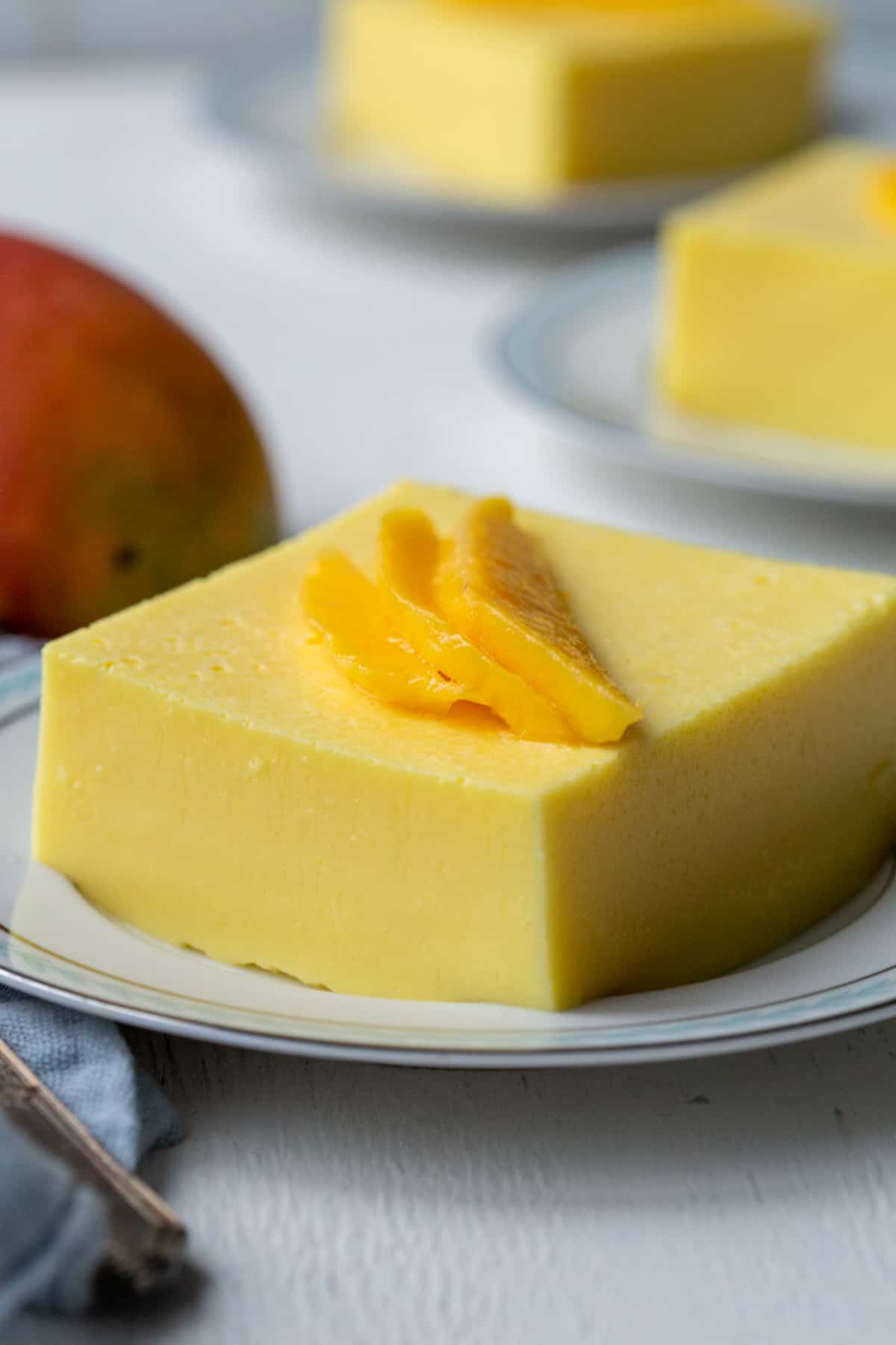 slice of creamy mango salad on a white plated, topped with a fresh mango garnish.