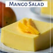 slice of creamy mango salad on a white plated, topped with a fresh mango garnish.