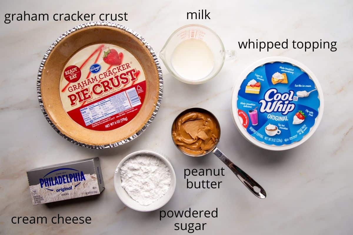 peanut butter, cream cheese, whipped topping, and other pie ingredients on a white table.