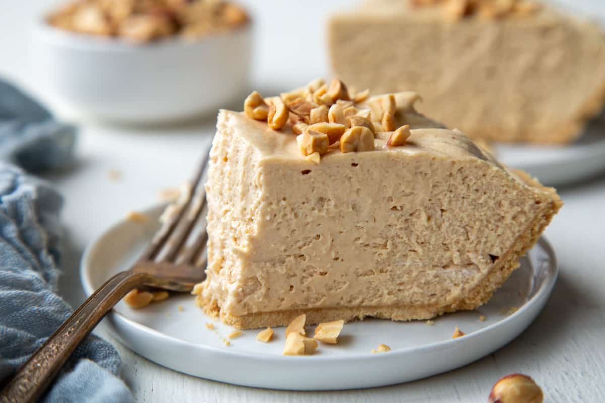 slice of peanut butter pie with a bite taken out of it, sitting on a white plate with a vintage fork next to it. 