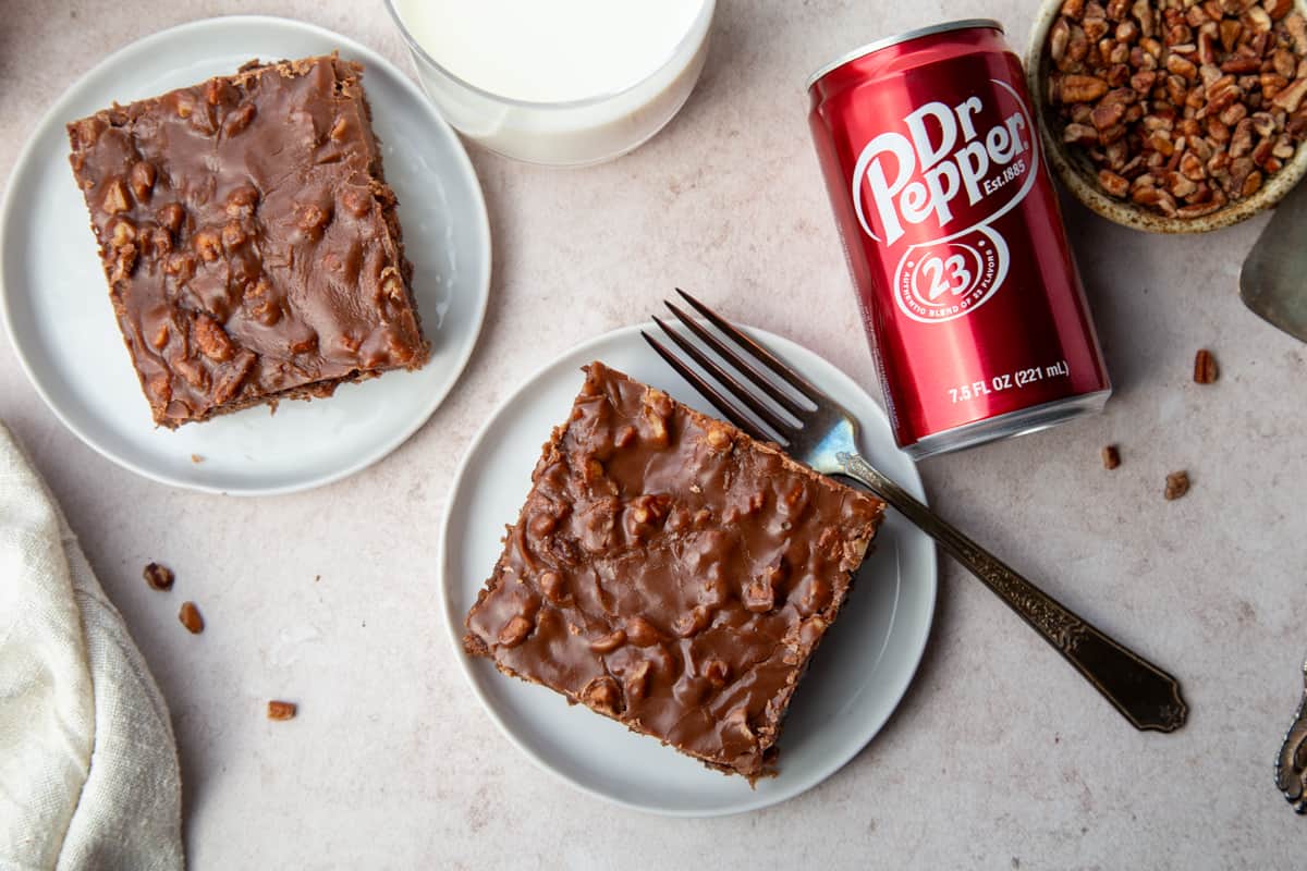 slices of dr. pepper cake on white plates next to a can of dr. pepper. 