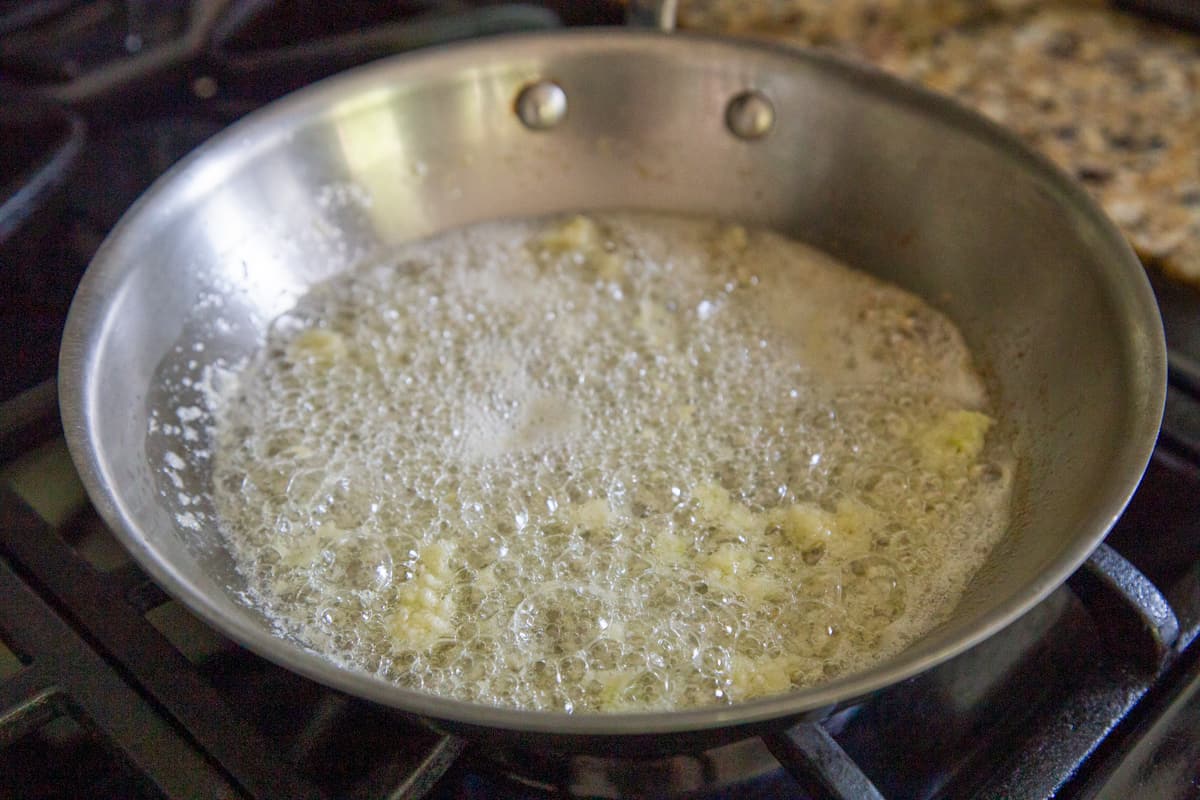 garlic frying in butter and oil in a skillet.