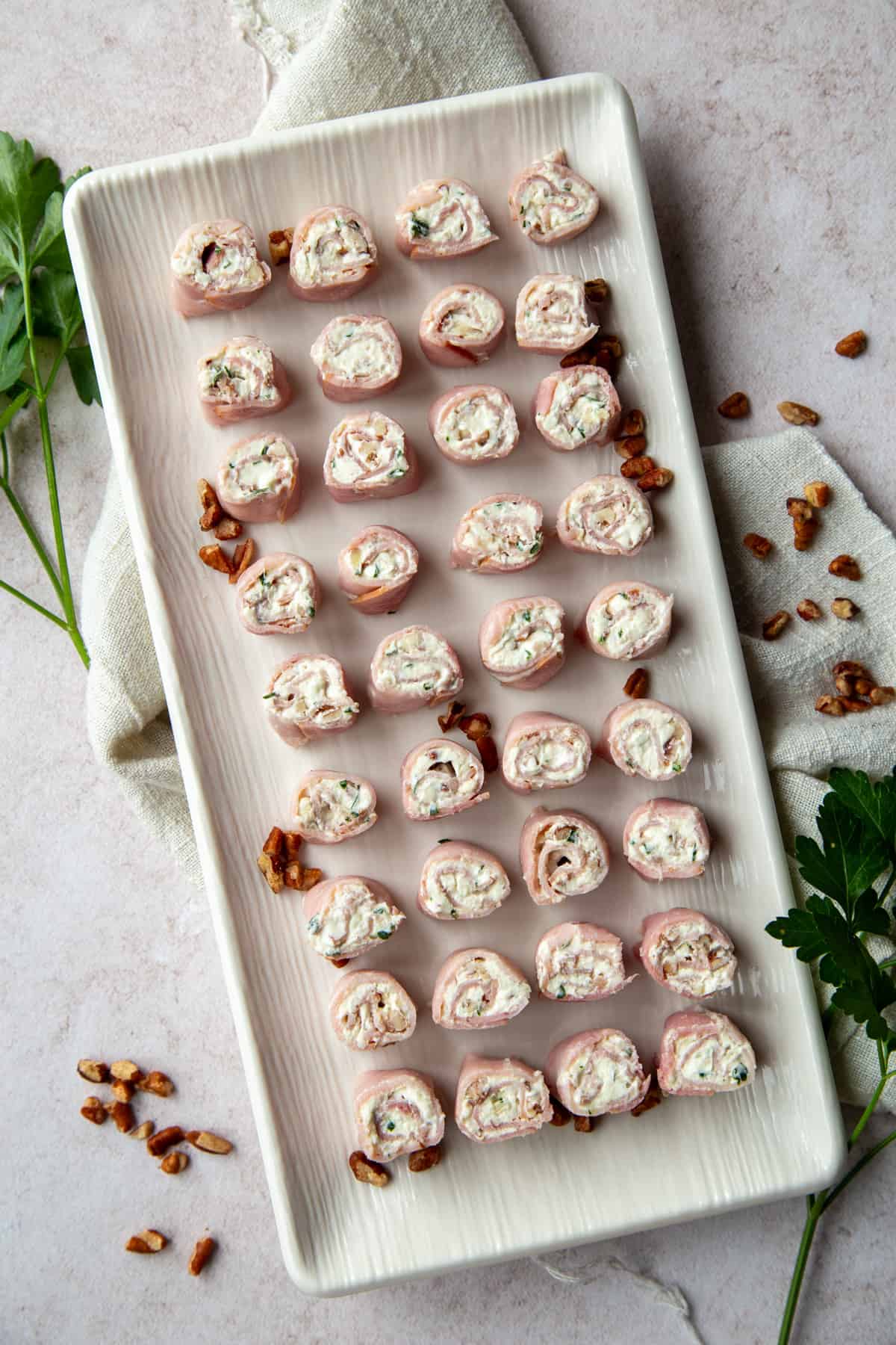 ham roll-ups lined up on a white rectangular platter.