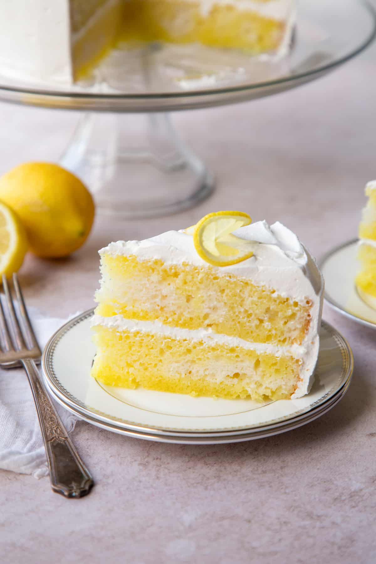 slice of layered lemon poke cake made with lemon gelatin on a white plate.