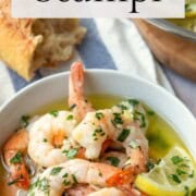 shrimp scampi with lemons in a white dish.