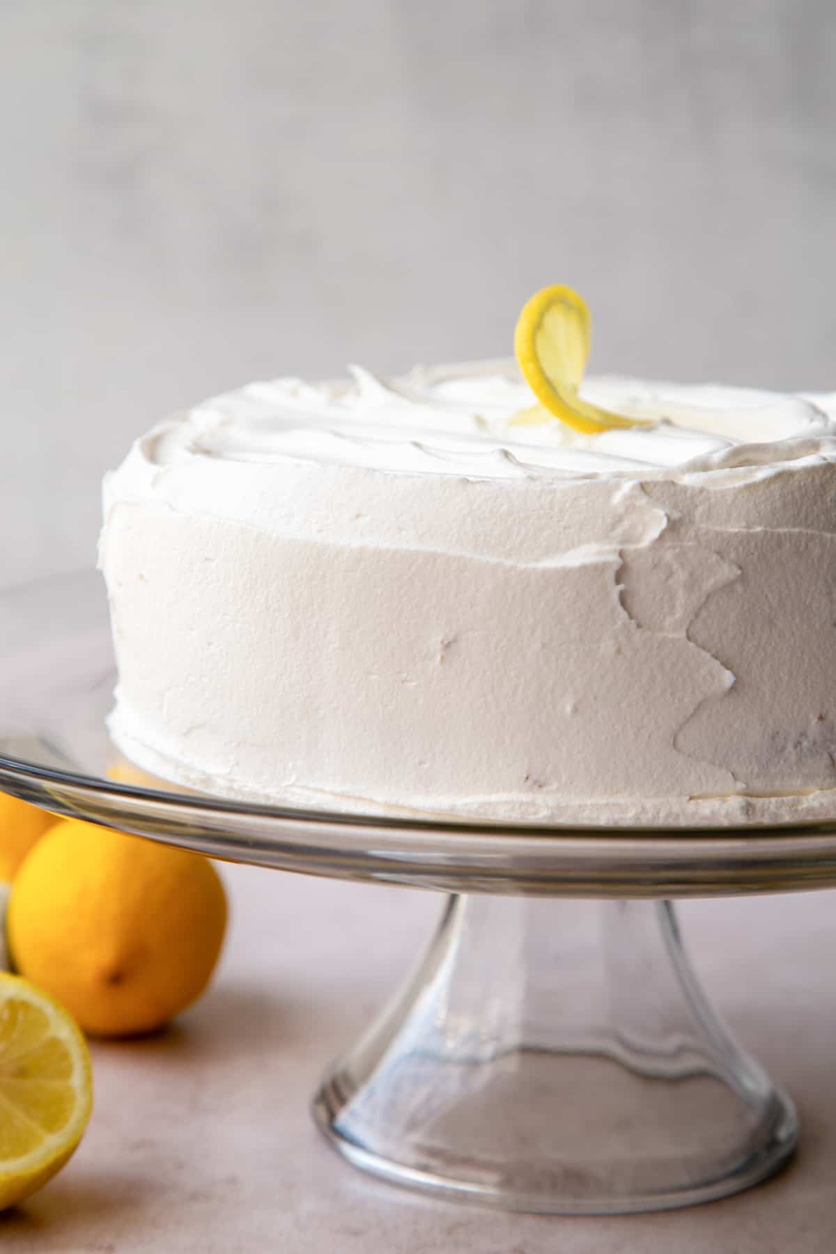 whole cake frosted with cool whip on a glass cake stand.