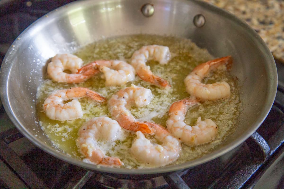 cooked shrimp frying in butter in a skillet.