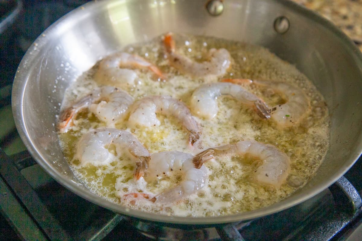 partially cooked shrimp in butter in a skillet.