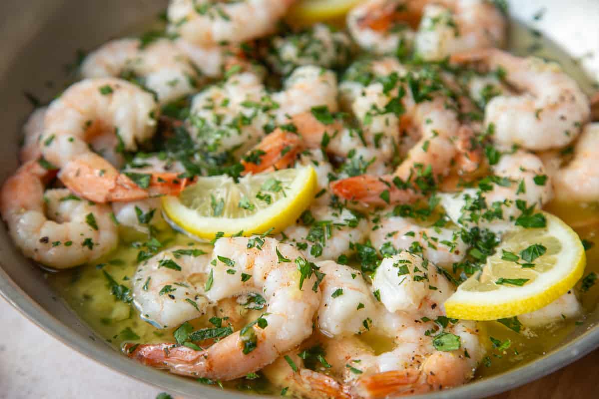 shrimp scampi and lemon slices in a metal skillet.