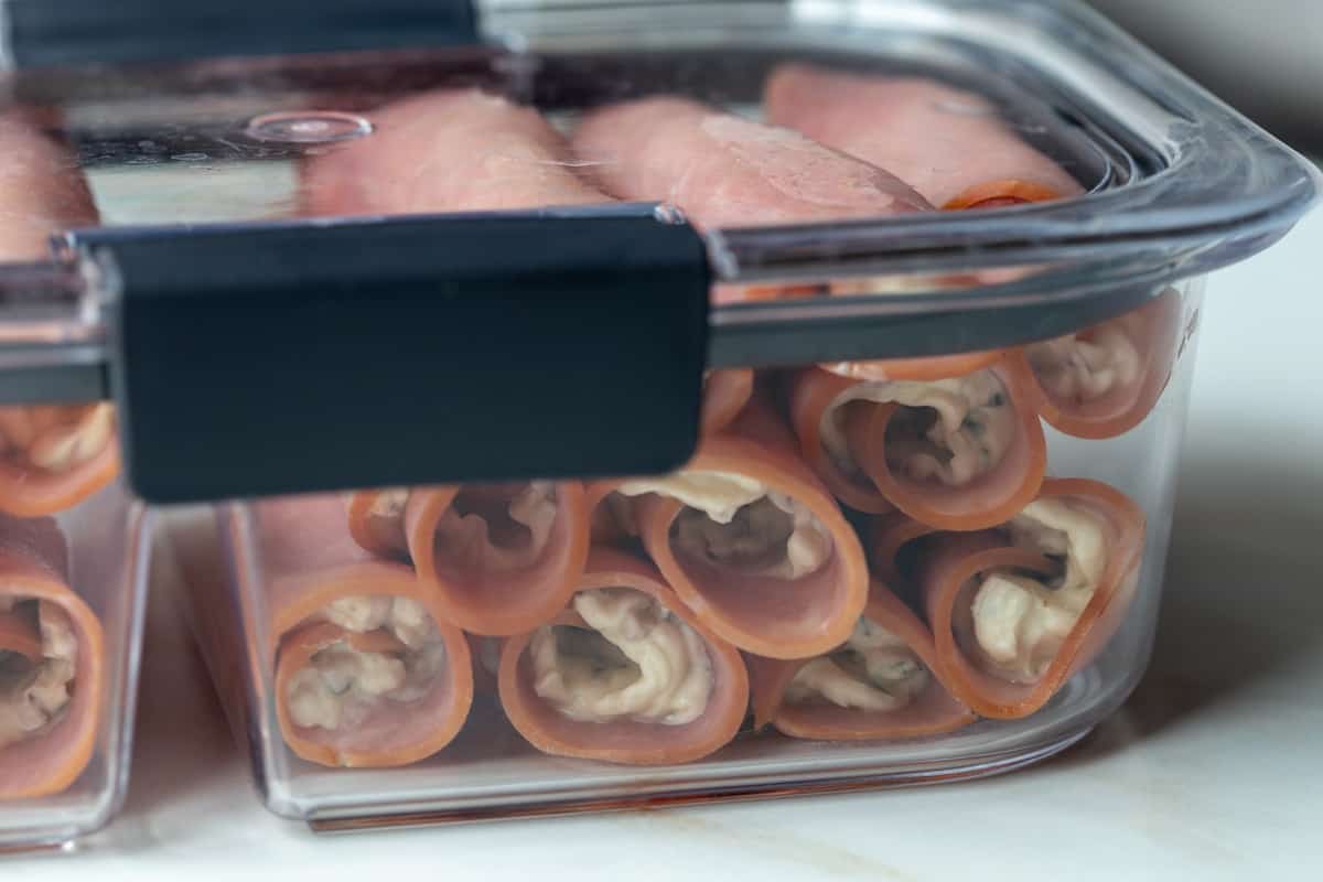 ham rolls stacked in a plastic storage container.