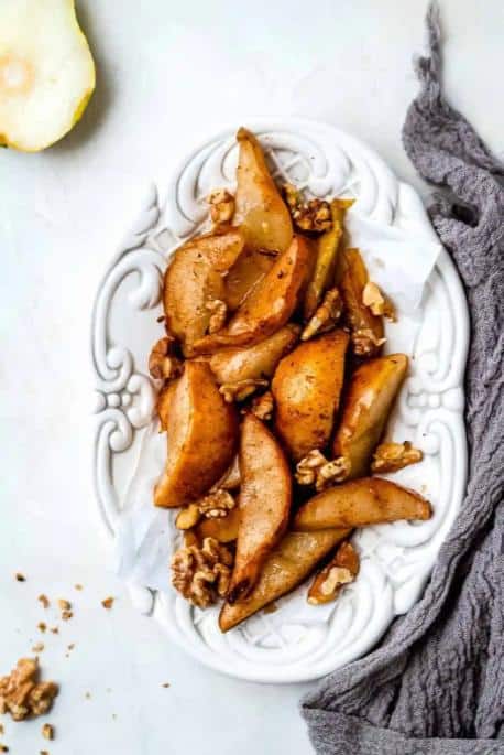 Top view of an ornate white plate filled with Baked Pears and Walnuts.