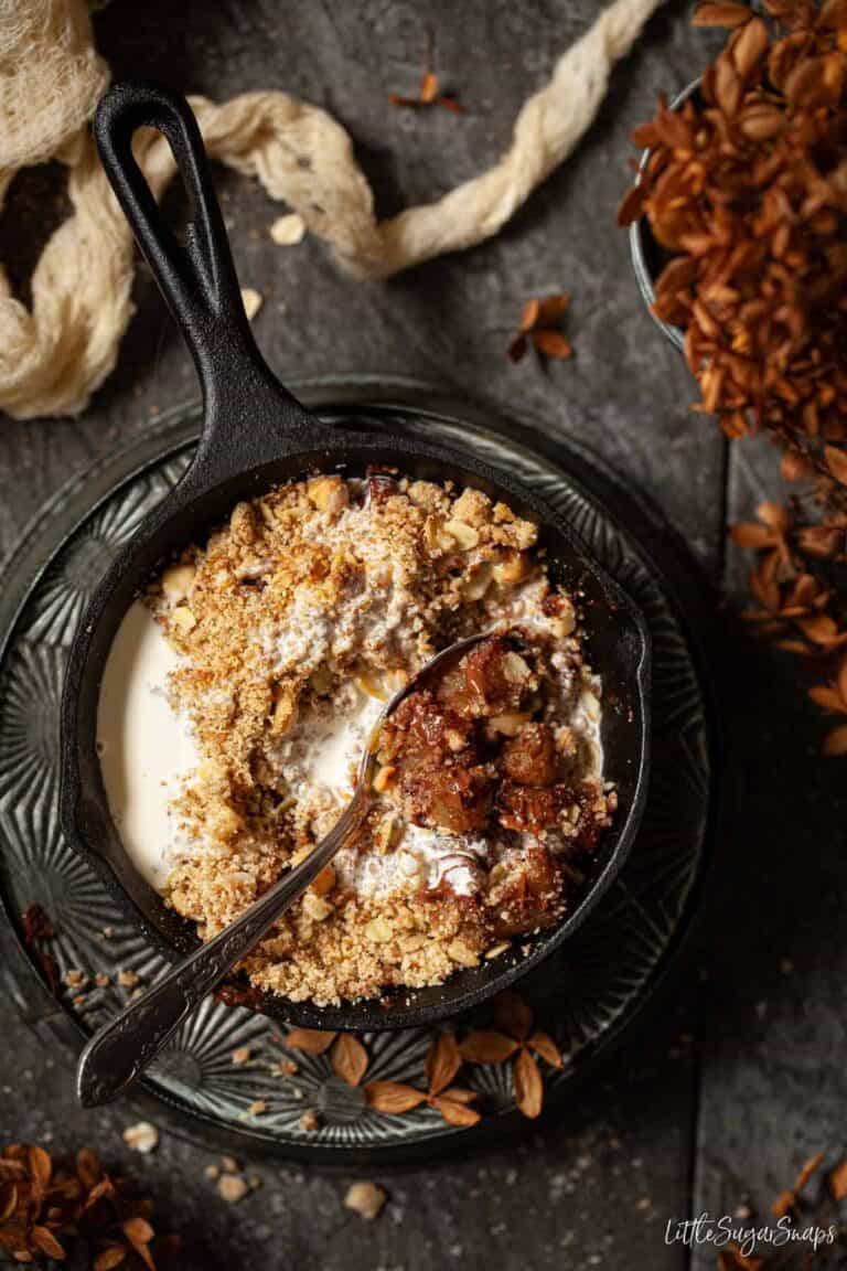 Top view of Pear Crumble with Chocolate in a small black skillet with a spoon inserted.