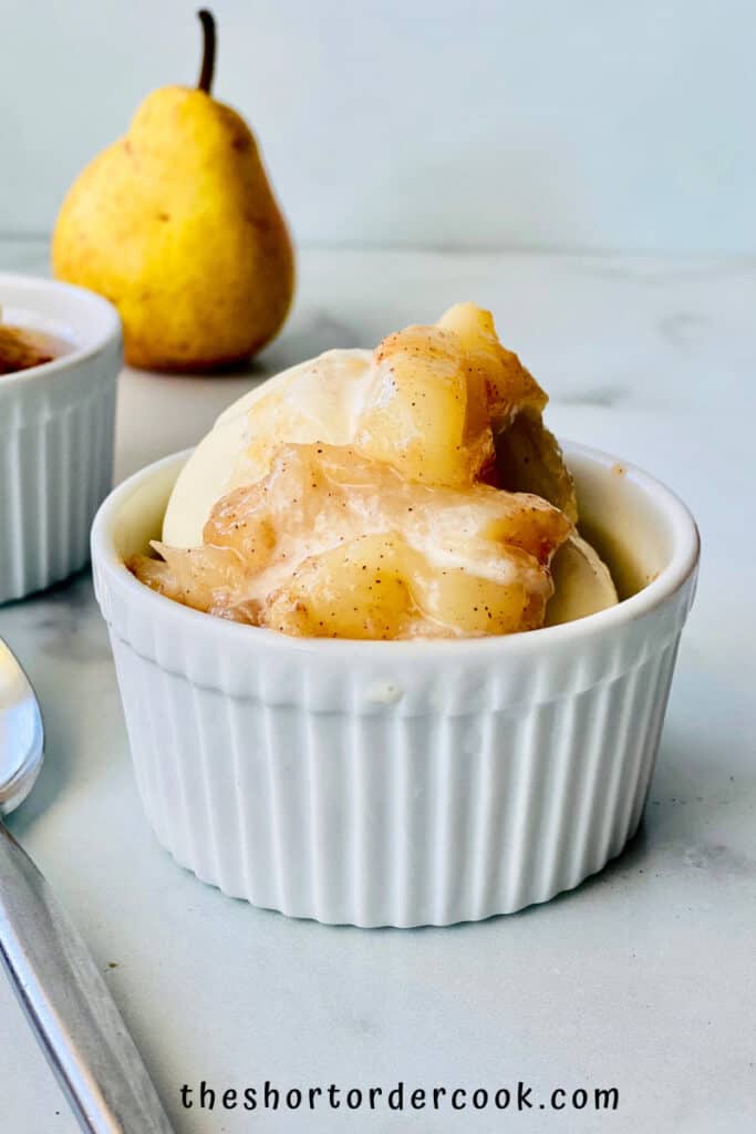 Stewed Pears poured over ice cream in a small white ramekin.