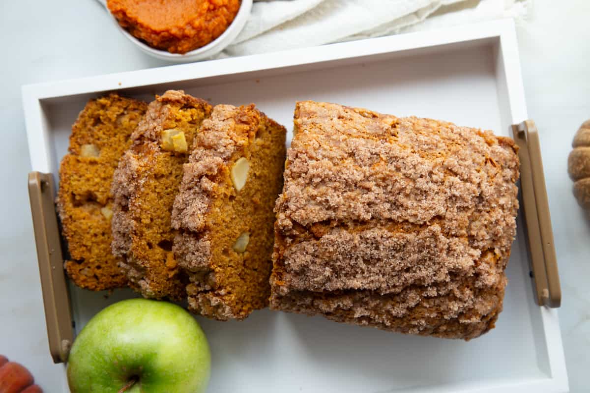 pumpkin apple bread loaf on a white wooden tray.