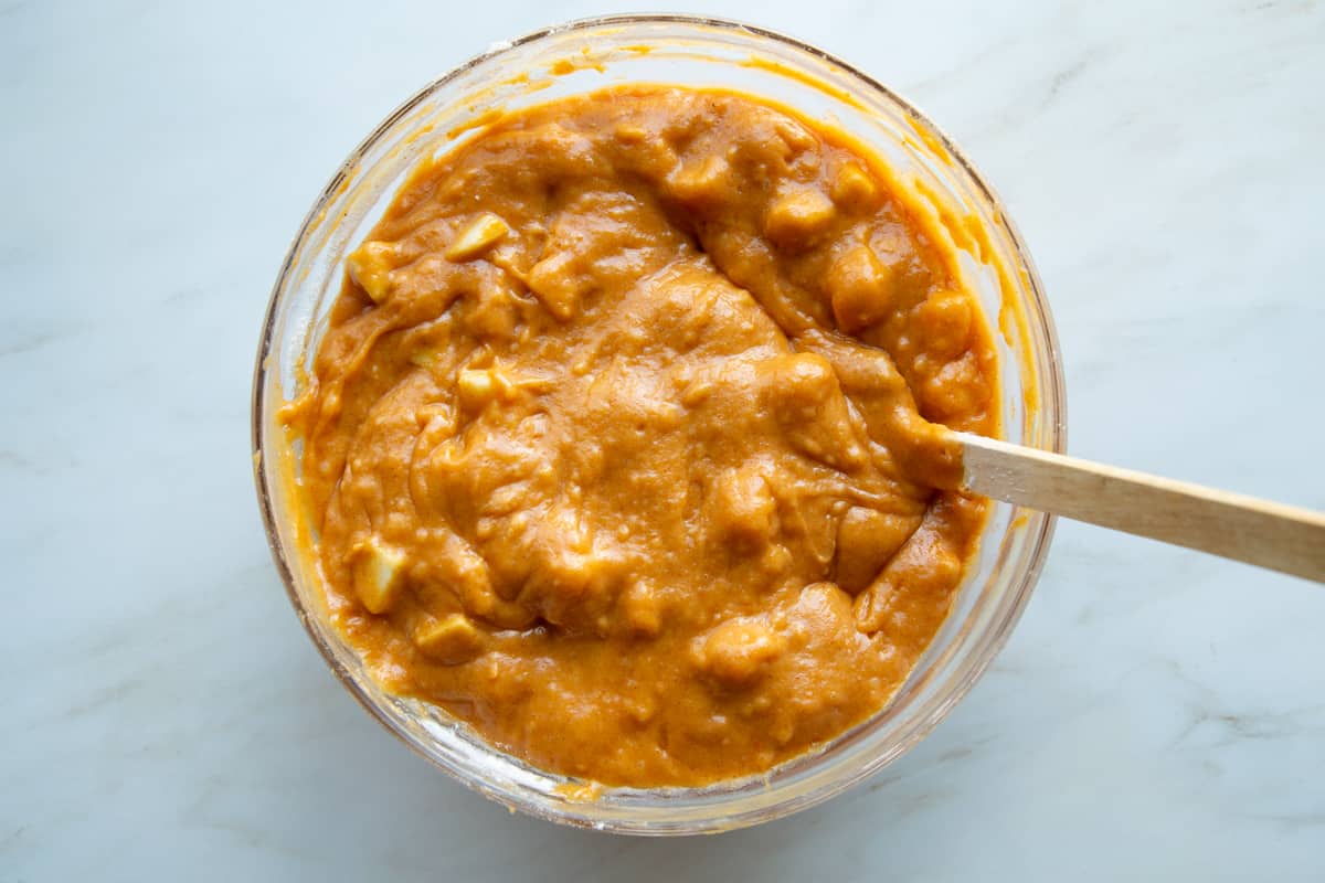 pumpkin batter with chopped apples in a glass bowl.