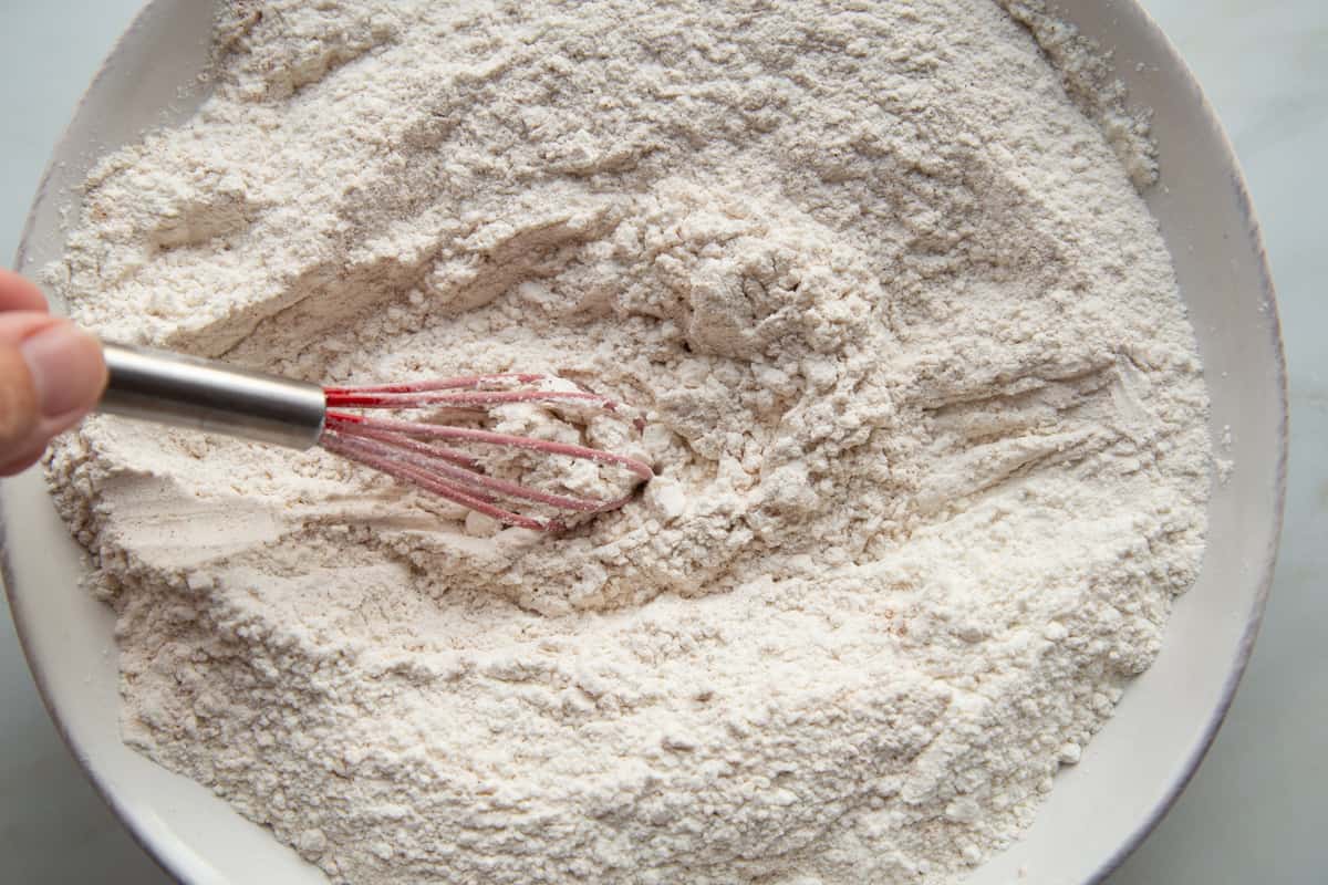flour mixture with a whisk in a shallow white bowl.