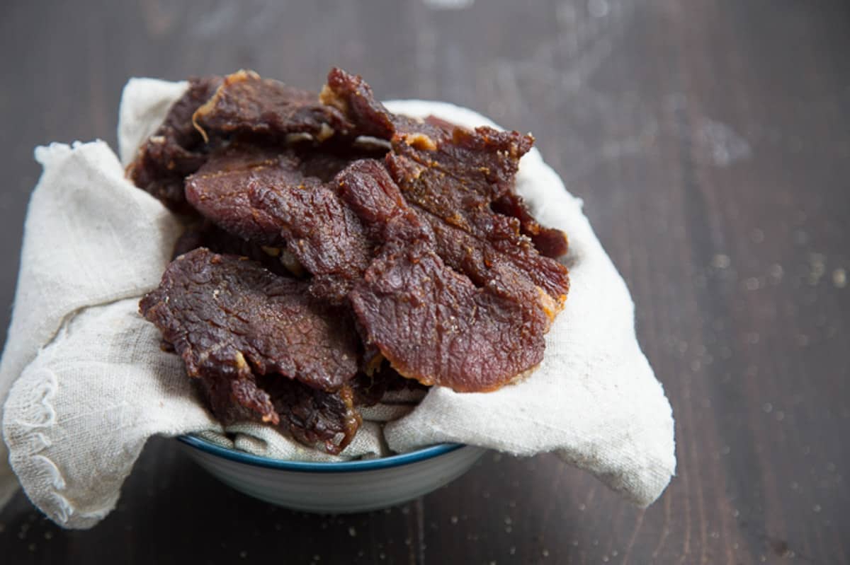 beef jerky on a beige linen towel in a bowl.