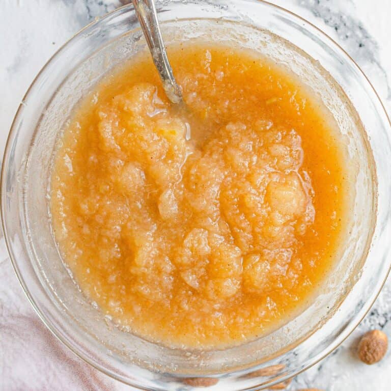 Top view of Pear Applesauce in a small glass bowl with a silver spoon inserted.