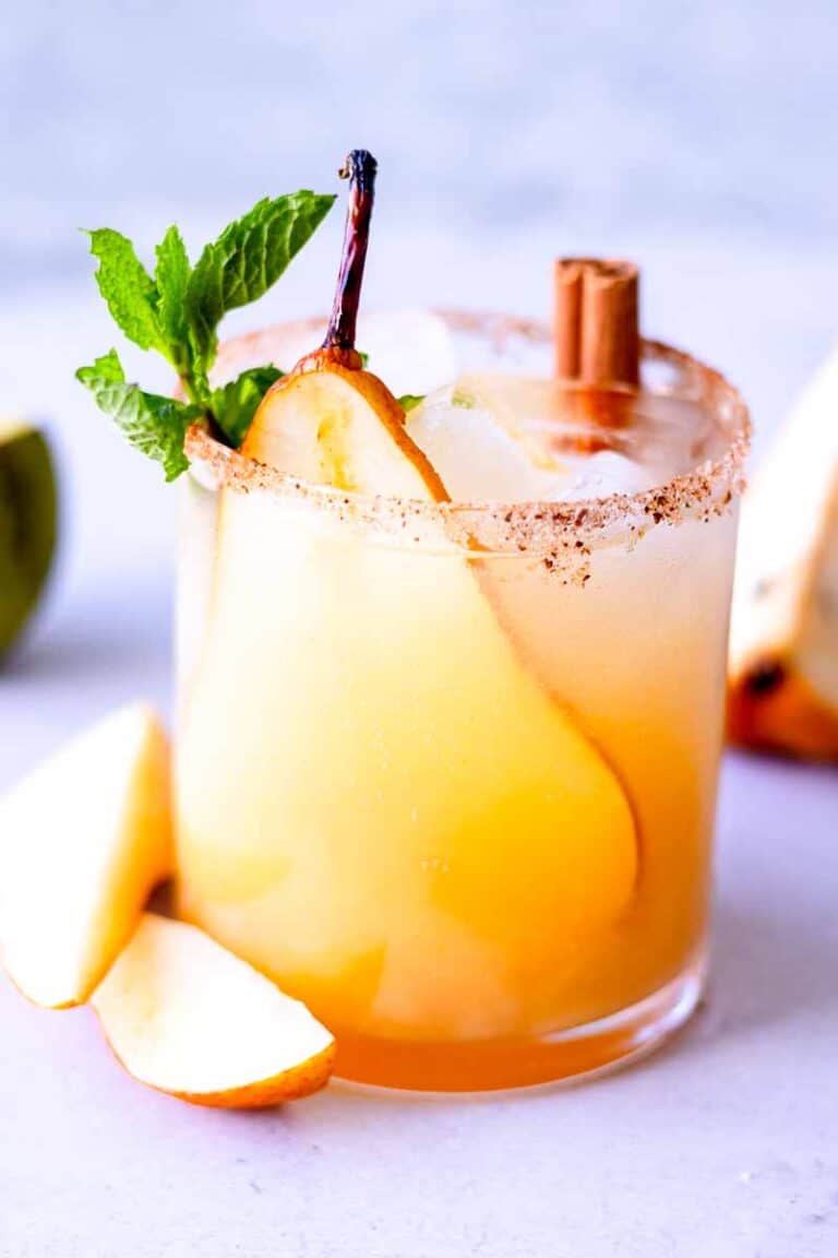 Side view of a small glass of Pear Ginger Beer Mocktail on a light blue surface.