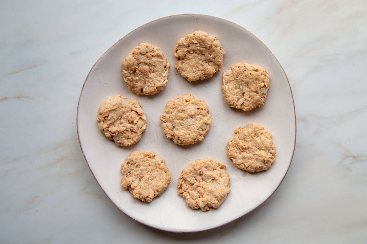 8 uncooked Salmon Patties on a plate.