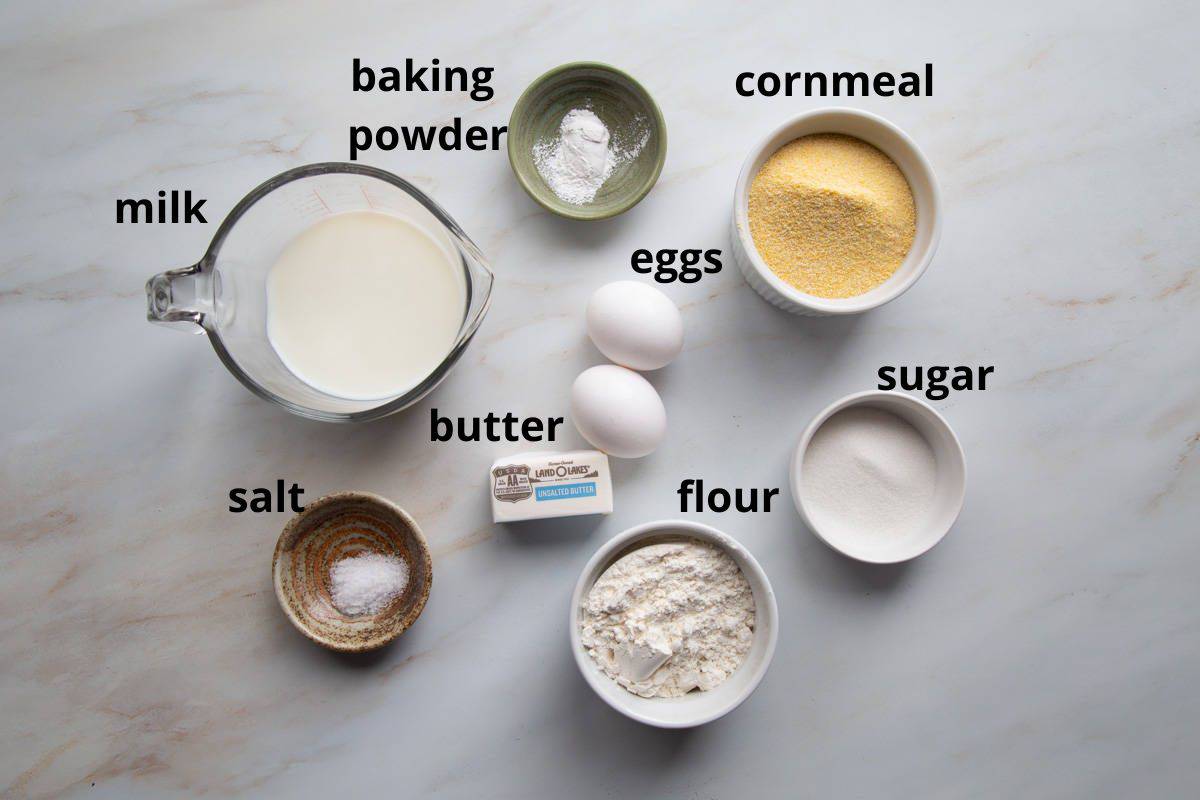 milk, cornmeal, flour, and other ingredients on a white table.