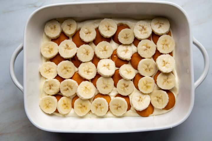 the first layer of pudding, cookies and bananas in a baking dish.