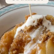 a drizzle of heavy cream being poured over a dish of pear crumble with a streusel topping.