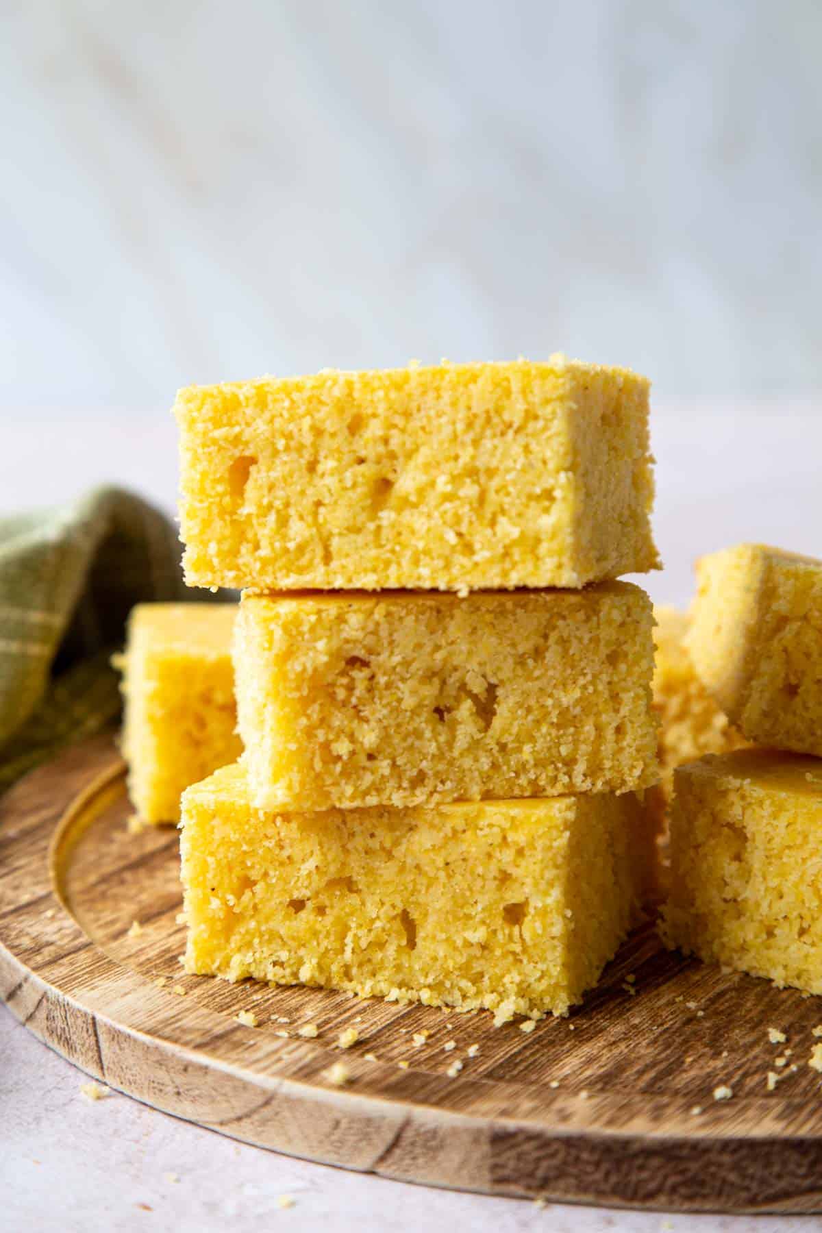 3 slices of cornbread stacked one on top of the other on a wooden surface.