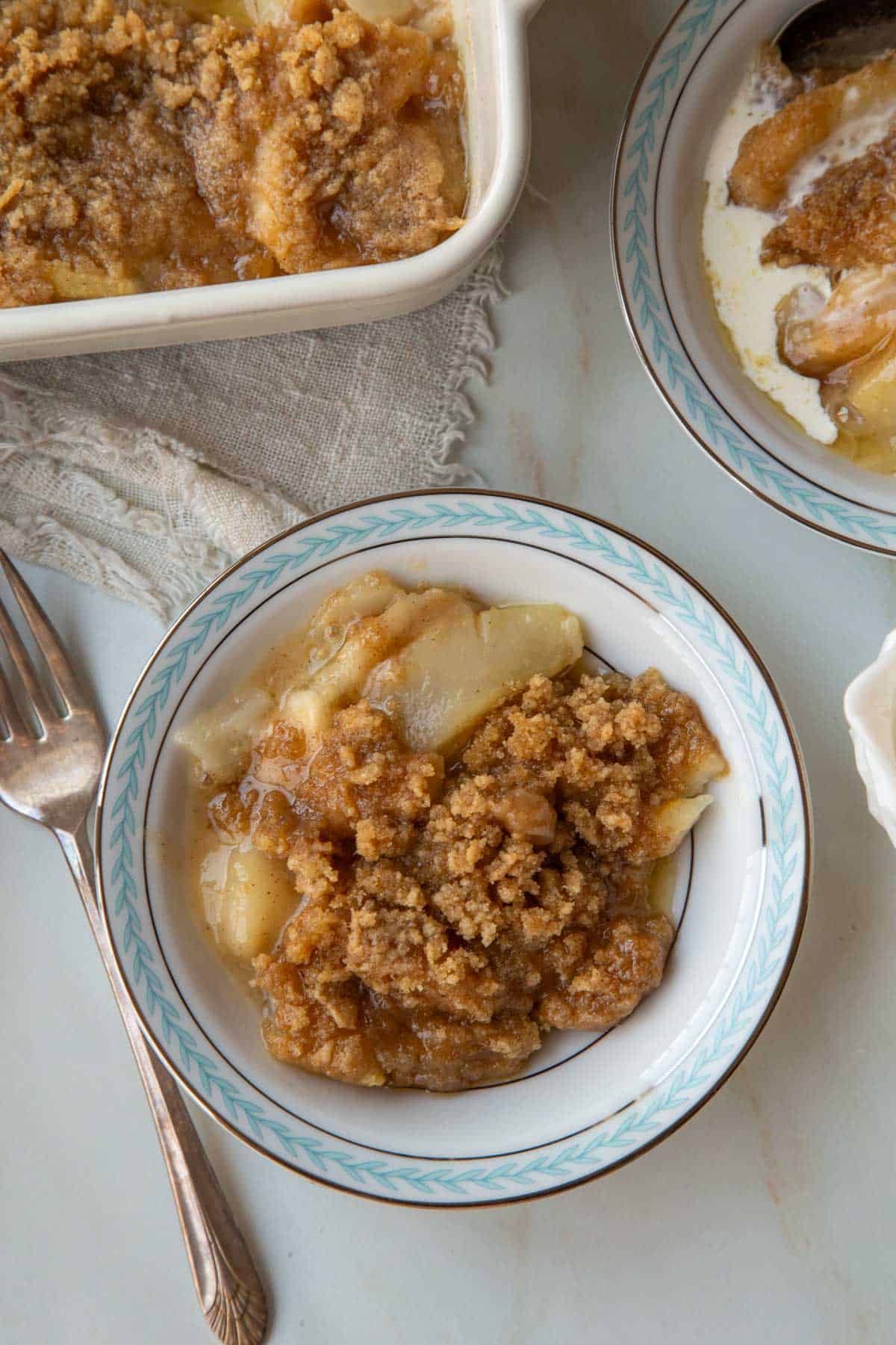 Top view of a serving of Pear Crumble in a white, silver, and blue bowl.