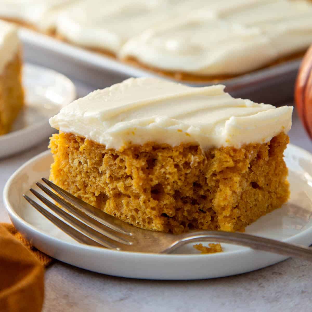 slice of pumpkin bar with cream cheese frosting, with a bite taken out.