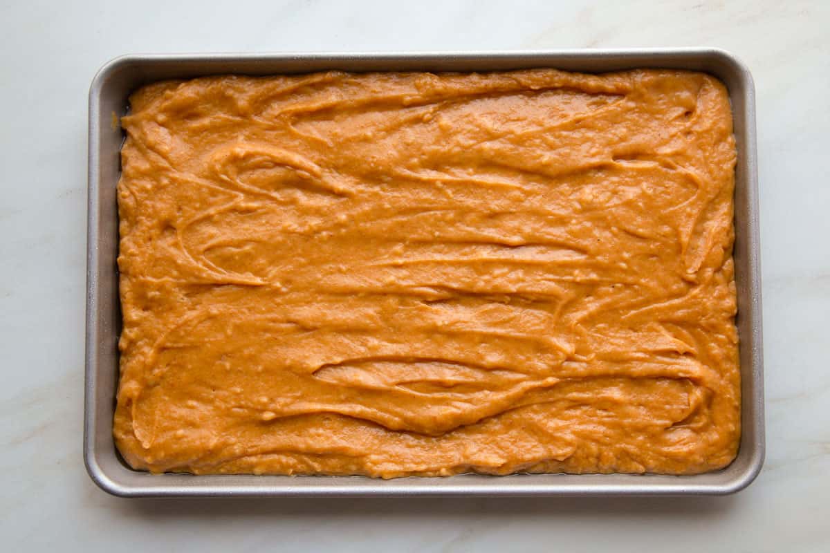 orange batter in a jelly roll pan.